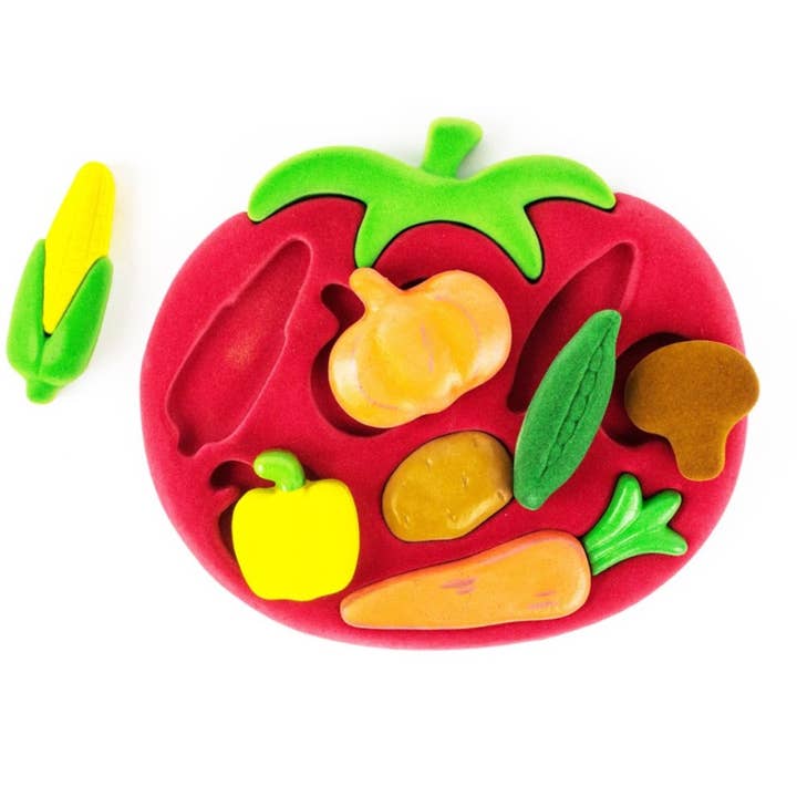 Vegetable theme shape sorter.  Shaped like a tomato, inlaid with smaller vegetables.  A bell pepper, a cob of corn, a pumpkin, a potato, a pod of peas, a carrot and a mushroom all have a spot!