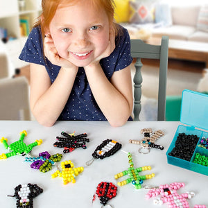 Image of child next to done bead crafts.  Animals shown here are a frog, dragonfly, cat, penguin, bird, spider, ladybug, lizard, rabbit, and mystery four-limbed beast. 