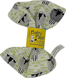 The sheep variety of Baby Paper.  A pale, cream-ish background with little tufts of green grass is interspersed with white and black sheep, all of whom look forward out at the viewer through pupilless eyes.  