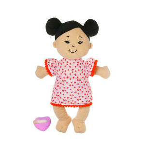 Baby Stella Light Beight with Black Buns outside of packaging.  The doll has black embroidered eyes and a smile.  She is where an orange dress with scalloped trim and oranges patterned on the cloth.  